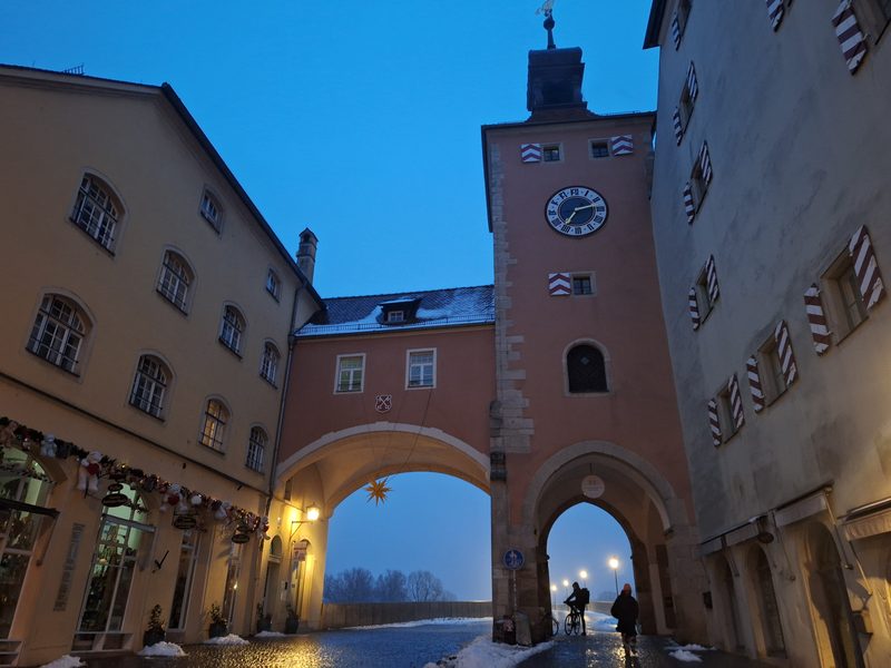Medieval door and tower giving way to the old stone bridge in Regensburg